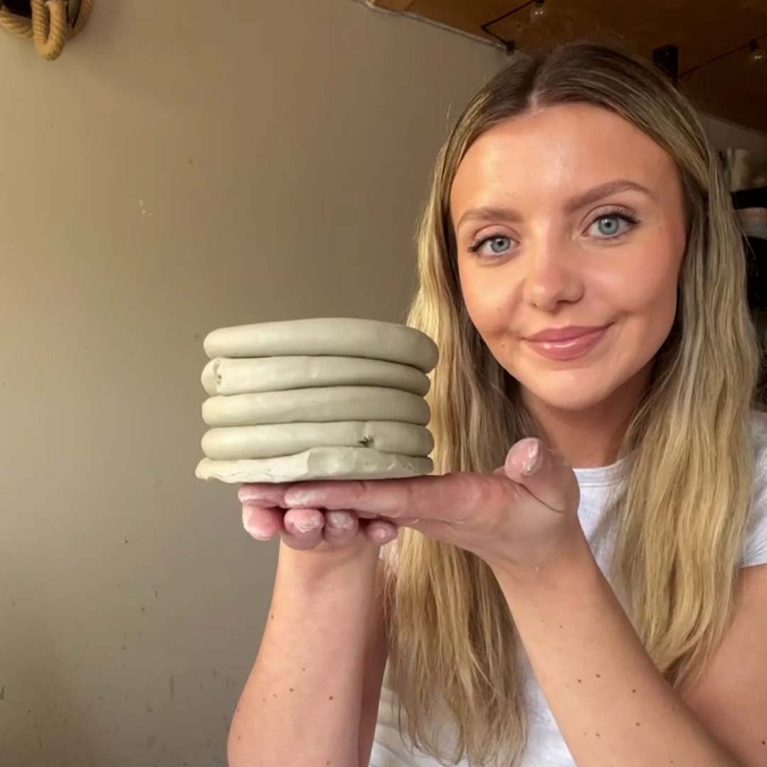 An artist holds aloft a clay piece made using Sculpd Pottery Kit