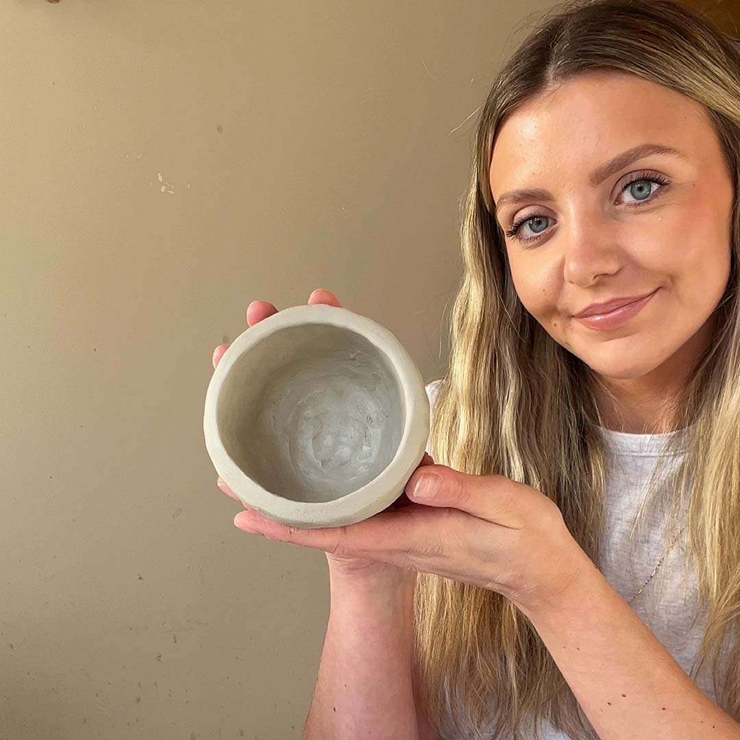 An artist holds aloft a clay piece made using Sculpd Pottery Kit