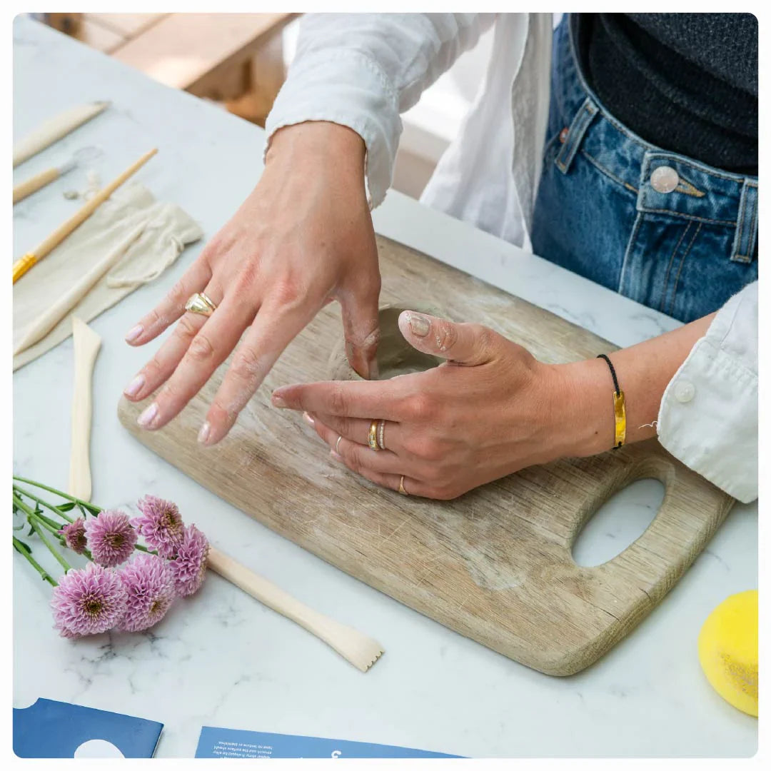 Hands demonstrating pottery techniques, with Sculpd tools and clay displayed on a table